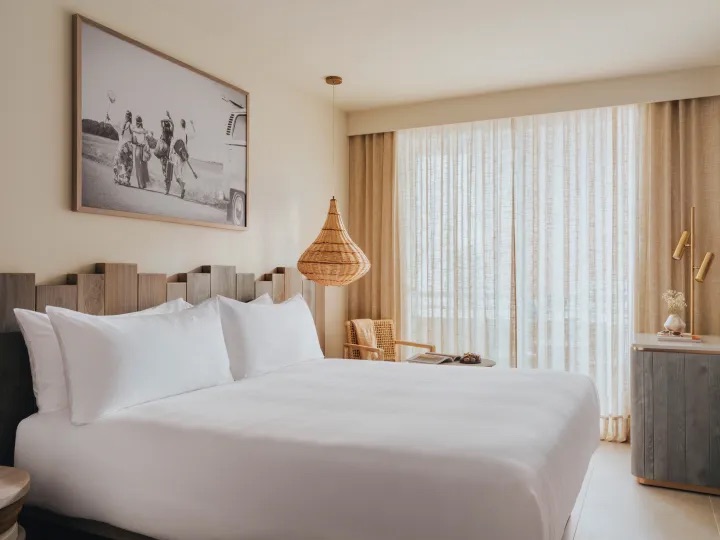 king sized bed with large art work hanging on the wall and ceiling light hanging above it