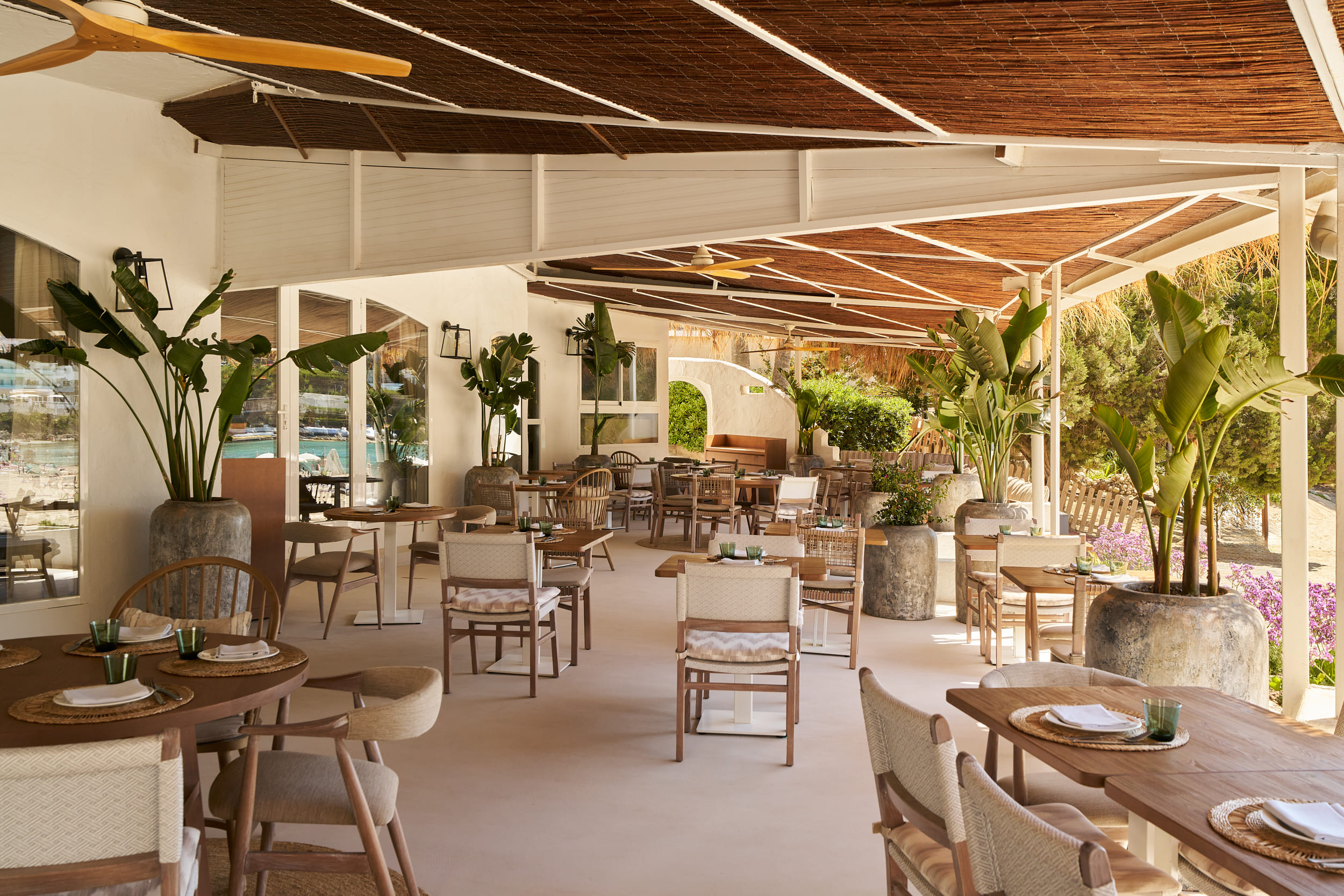 Covered outside terrace of restaurant with many tables and chairs
